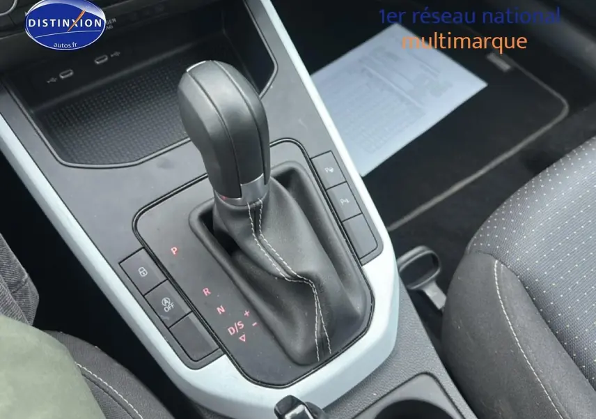 Levier de boîte automatique noir avec surpiqûres blanches dans l’habitacle d’une SEAT Arona bleu saphir 2025.