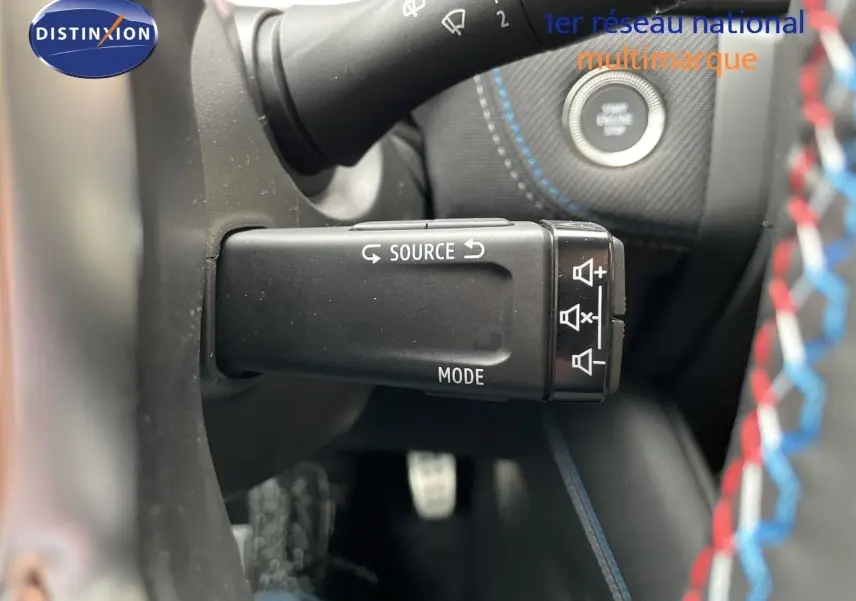 Gros plan sur la commande multimédia au volant du Renault Symbioz gris Rafale, avec démarreur et coutures bleues visibles.