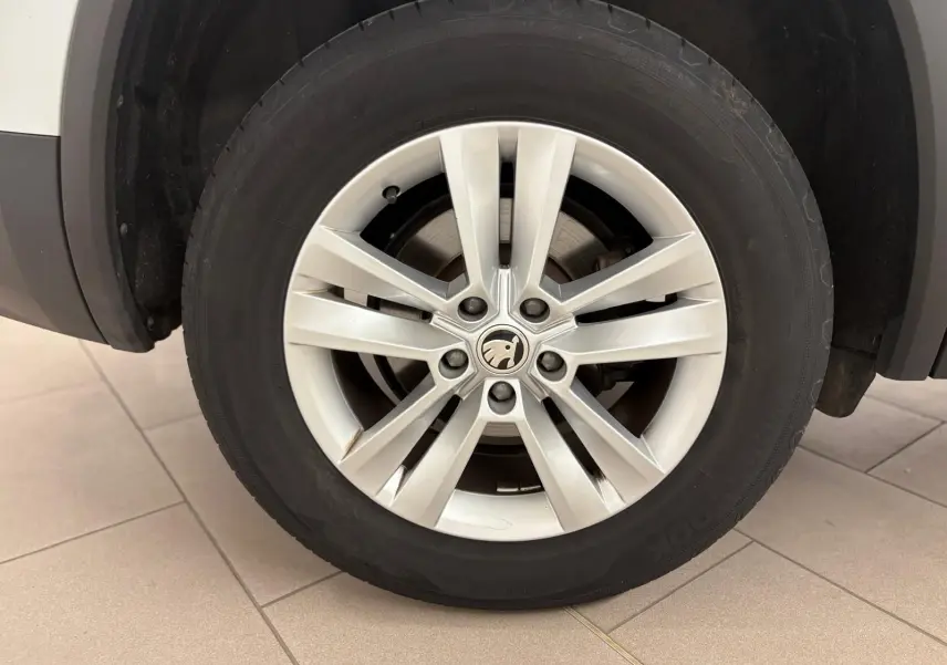 Gros plan sur la roue avant gauche du Skoda Kodiaq blanc Lune, mettant en valeur la jante alliage à 10 branches.