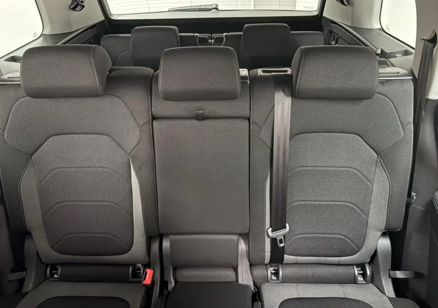 Vue arrière des sièges noirs du rang 2 du Skoda Kodiaq blanc lune 2022 avec banquette rabattable et ceinture visible.