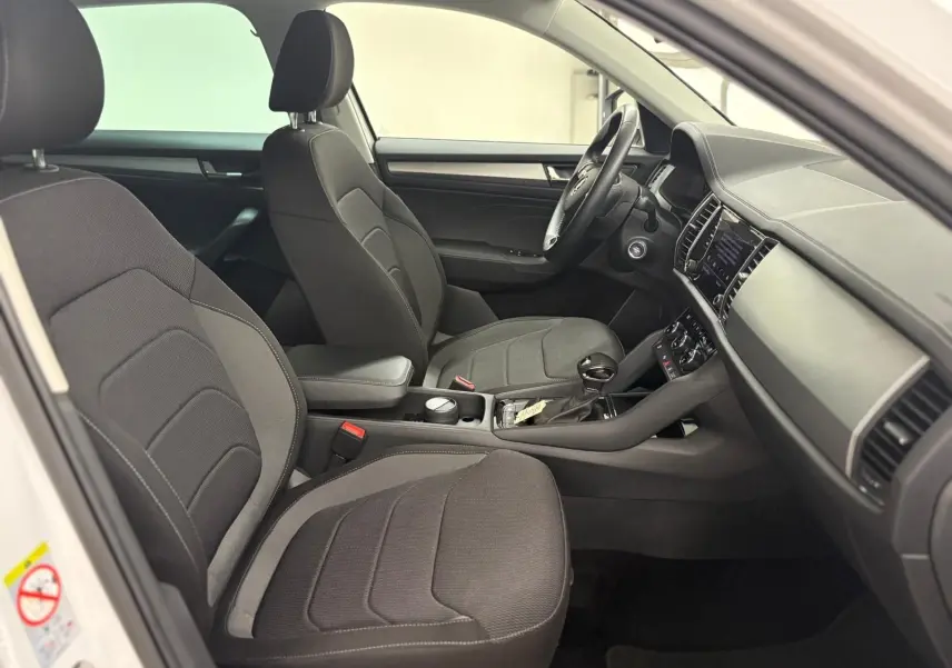 Intérieur côté conducteur du Skoda Kodiaq blanc lune 2022, sièges noirs et tableau de bord avec écran digital.