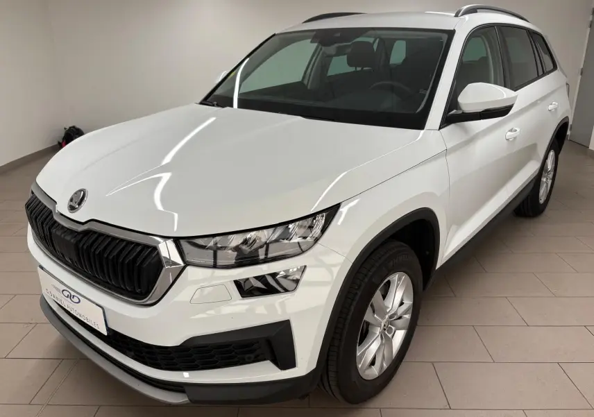 SKODA KODIAQ blanc lune vu en 3/4 avant droit dans un intérieur, avec calandre noire et jantes argentées.