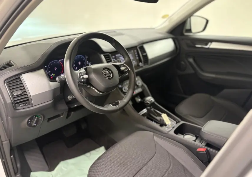 Intérieur avant droit du Skoda Kodiaq blanc lune 2022, avec tableau de bord moderne et volant multifonction noir.