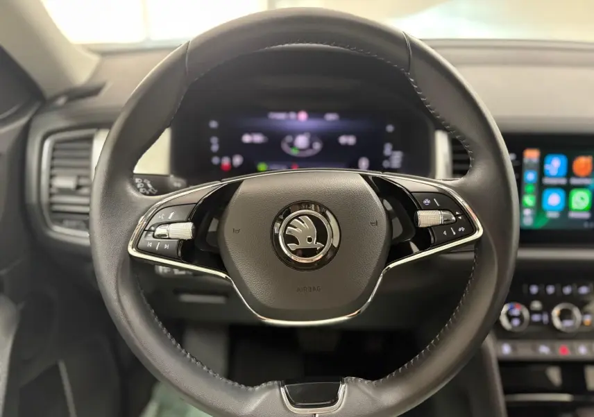 Gros plan sur le volant cuir noir du Skoda Kodiaq avec logo central et tableau de bord digital en arrière-plan.