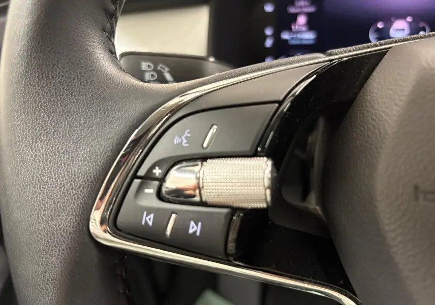 Gros plan sur les commandes du volant du Skoda Kodiaq 2022, mettant en valeur la molette métallique et les boutons rétroéclairés.