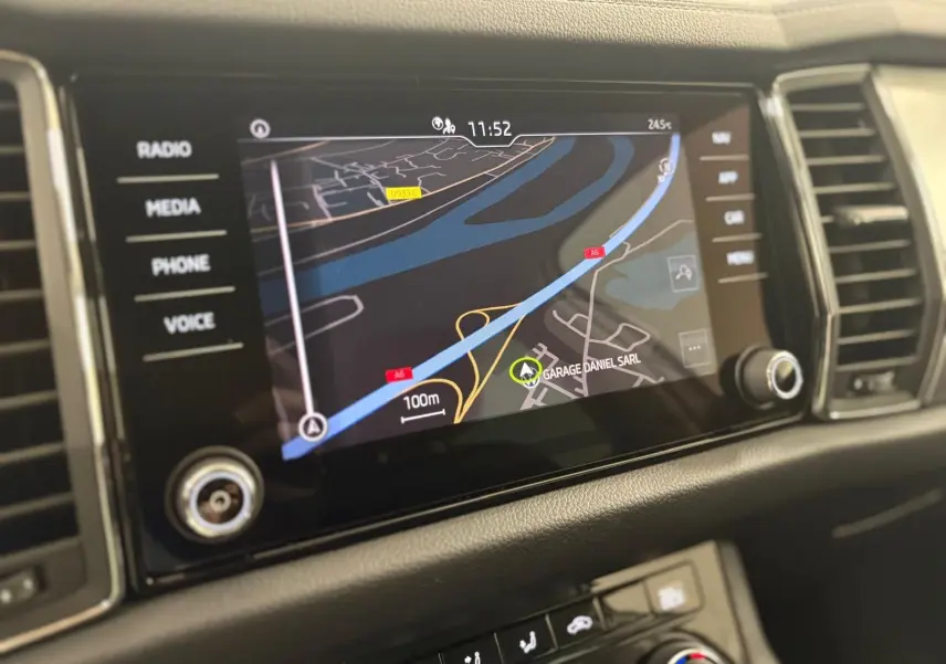 Écran tactile central du Skoda Kodiaq blanc lune 2022 affichant la navigation GPS avec commandes autour.
