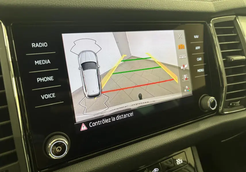 Écran tactile du tableau de bord du Skoda Kodiaq blanc lune 2022 montrant la caméra de recul avec lignes de guidage colorées.