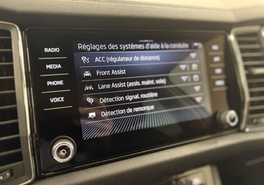 Écran tactile central du Skoda Kodiaq blanc Lune 2022 affichant les réglages d'aide à la conduite.