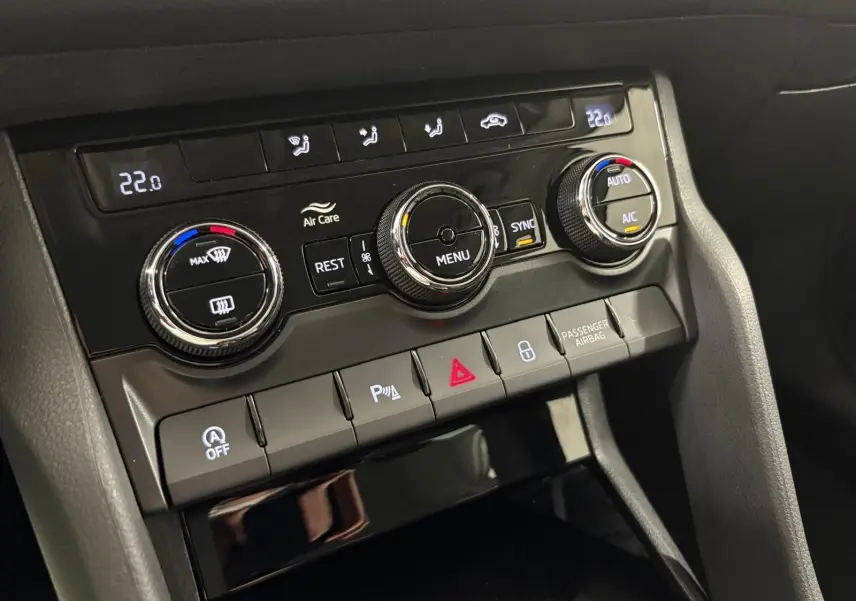 Gros plan sur la console centrale du Skoda Kodiaq blanc lune, montrant les commandes de climatisation et les boutons fonctionnels.