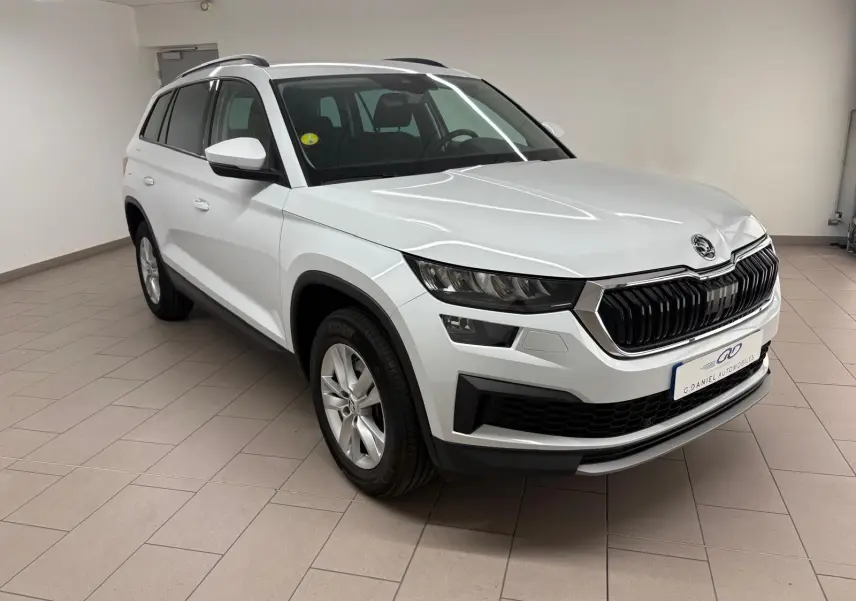 Vue 3/4 avant d'un Skoda Kodiaq blanc lune 2022 en intérieur, avec calandre noire et jantes argentées.
