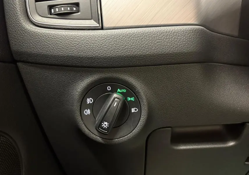 Gros plan sur le bouton de commande des phares dans l'habitacle noir du Skoda Kodiaq blanc Lune 2022.