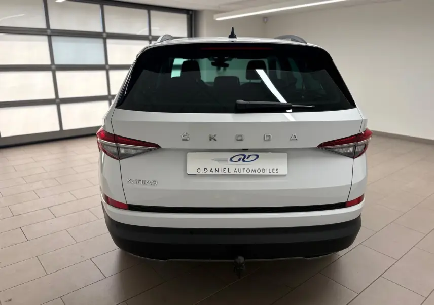 Vue arrière d'un Skoda Kodiaq blanc lune 2022 avec attelage escamotable et feux arrière LED dans un garage.