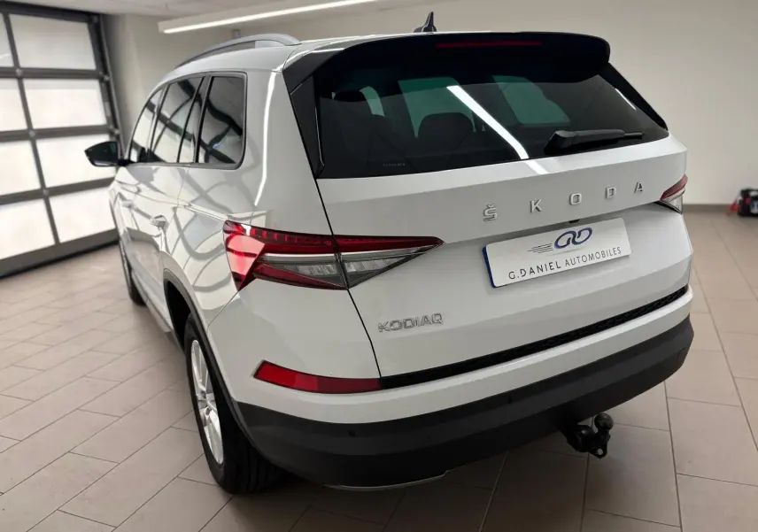 Vue 3/4 arrière droite d'un Skoda Kodiaq blanc Lune 2022 avec crochet d'attelage escamotable en intérieur showroom.