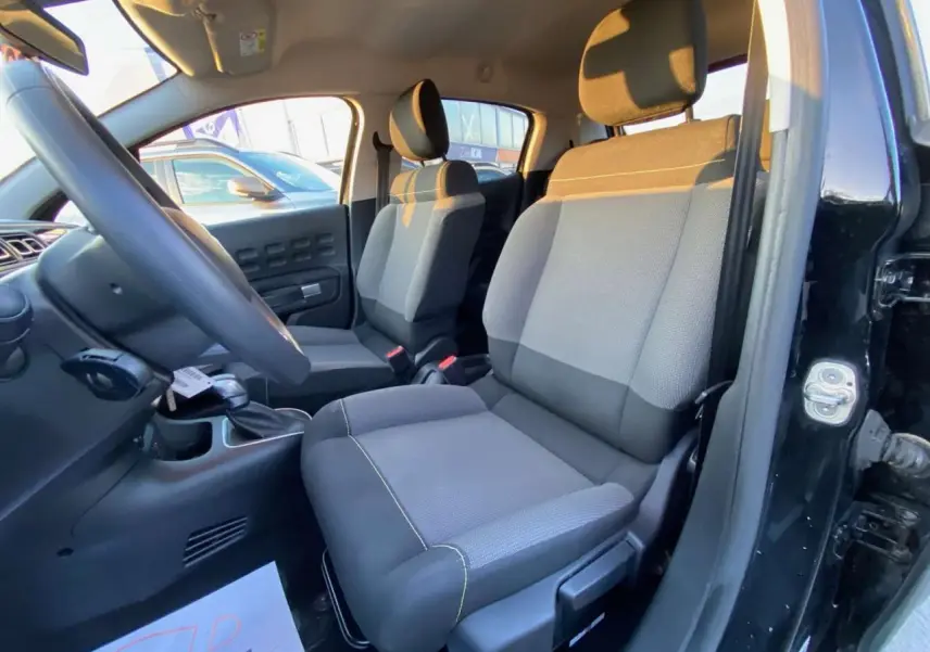 Intérieur avant droit de la Citroën C3 Shine 2023, sièges tissu gris et noir avec volant visible.
