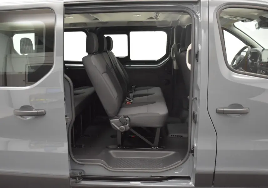 Vue latérale gauche du Renault Trafic Fourgon gris clair 2025, portes ouvertes montrant la banquette 3 places rabattable de la 3ème rangée.