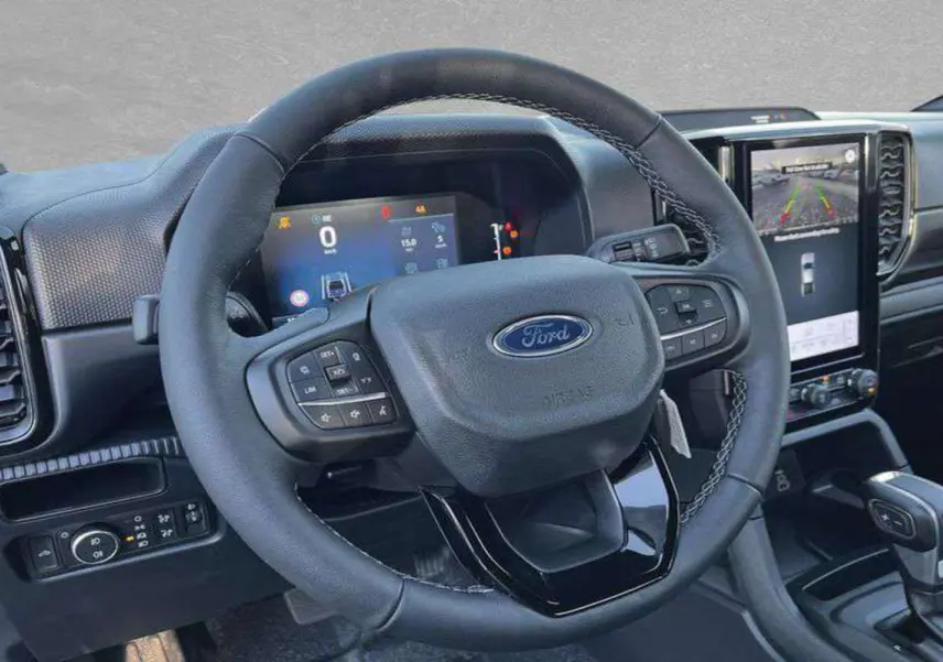 Vue intérieure centrée sur le volant cuir multifonctions du Ford Ranger 2025 avec écran tactile et tableau de bord numérique.