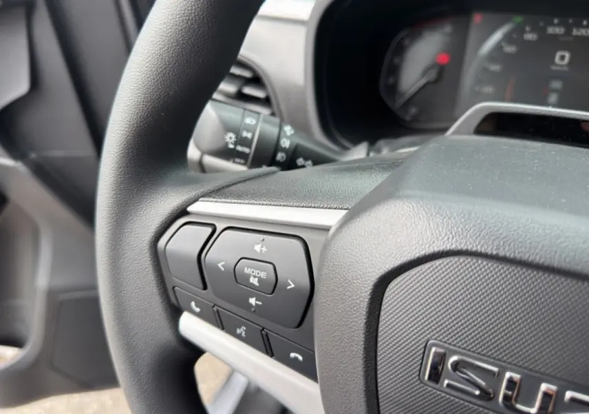 Gros plan sur le volant multifonctions côté gauche de l'Isuzu D-MAX 2026, avec commandes audio et téléphone.