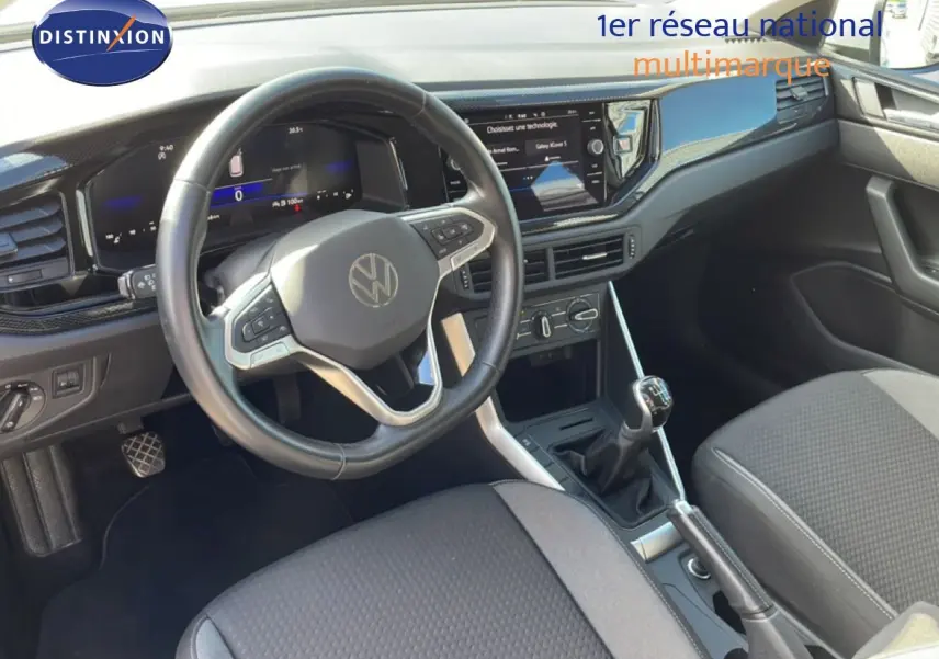Vue intérieure côté conducteur du Volkswagen Taigo 2022, tableau de bord noir avec volant cuir et boîte manuelle visible.