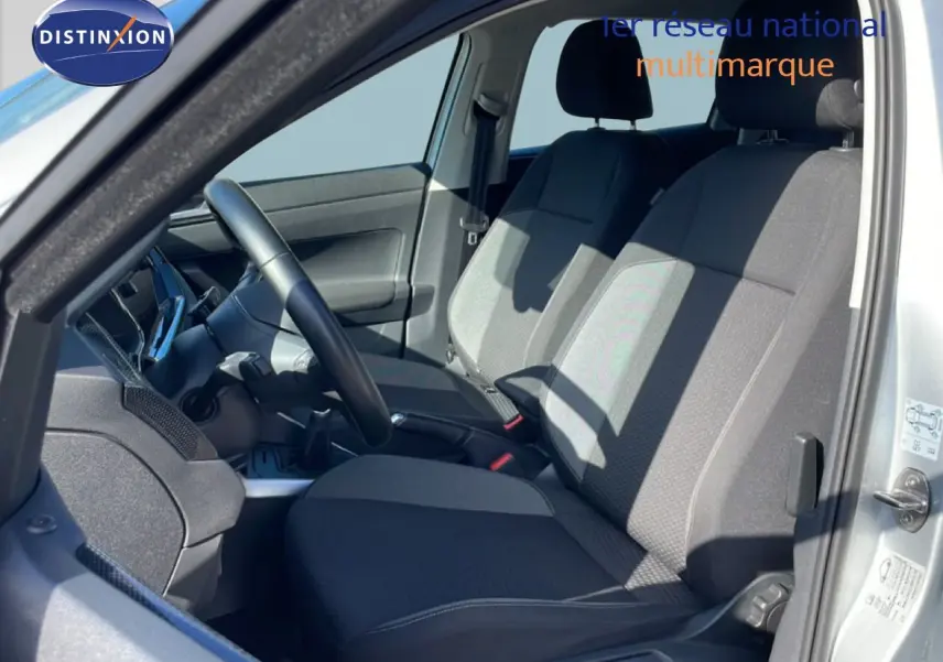 Vue intérieure côté gauche du Volkswagen Taigo 2022 argent, montrant les sièges avant en tissu gris et le volant cuir.