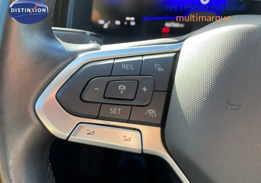 Gros plan sur les commandes au volant côté gauche du Volkswagen Taigo 2022 en reflet d'argent métal, avec boutons de régulateur de vitesse.
