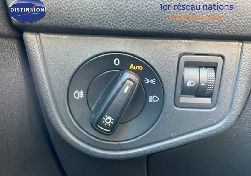 Gros plan sur le bouton de commande des phares avec réglage automatique dans l'habitacle noir d'un Volkswagen Taigo.