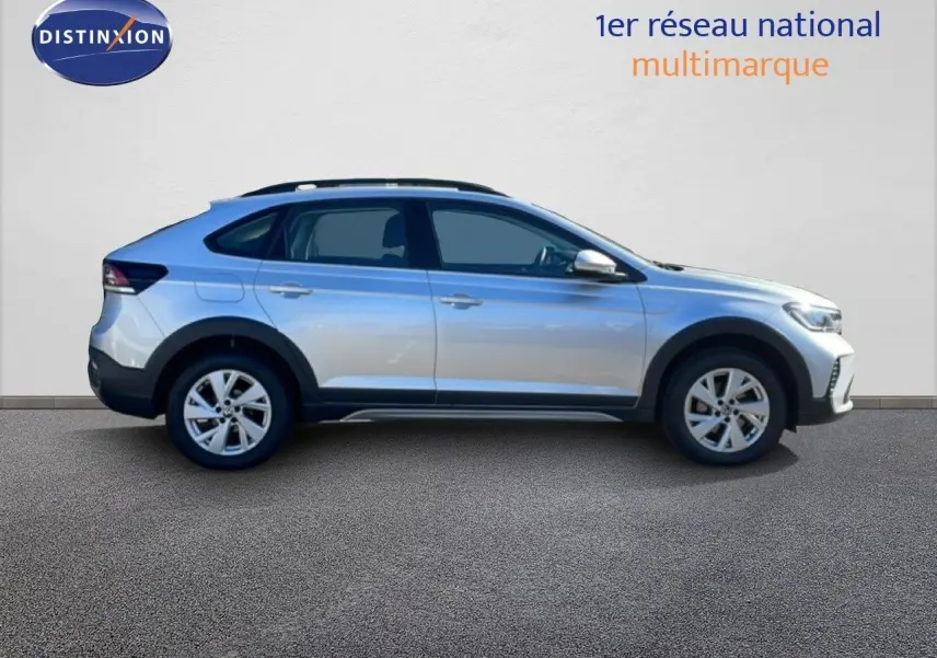 Vue de profil côté gauche d'un Volkswagen Taigo 2022 couleur reflet d'argent métal avec jantes alliage et barres de toit.