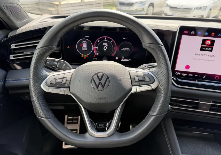 Vue intérieure centrée sur le volant cuir multifonction du Volkswagen Tiguan 2025 avec écran digital et console tactile.