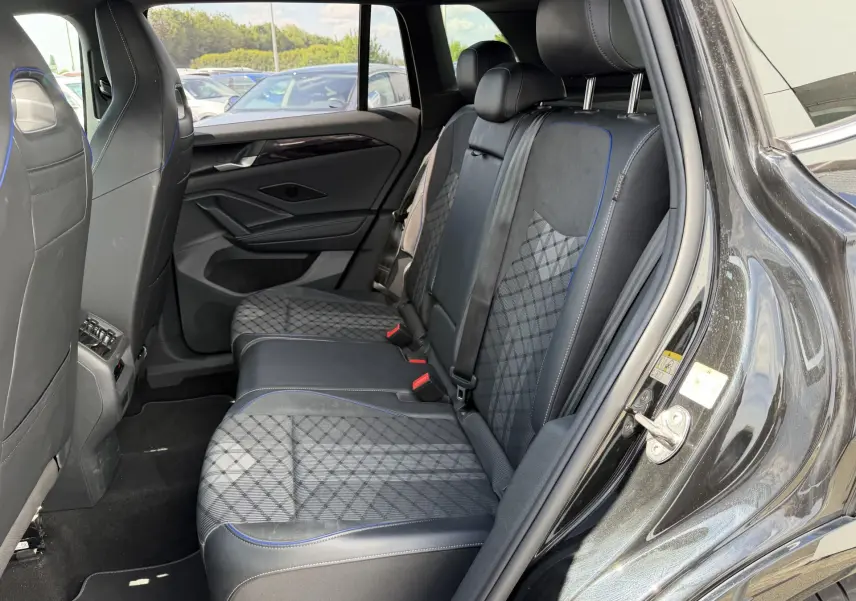 Vue intérieure côté droit des sièges arrière en tissu et cuir noir avec surpiqûres bleues du Volkswagen Tiguan 2025 noir.