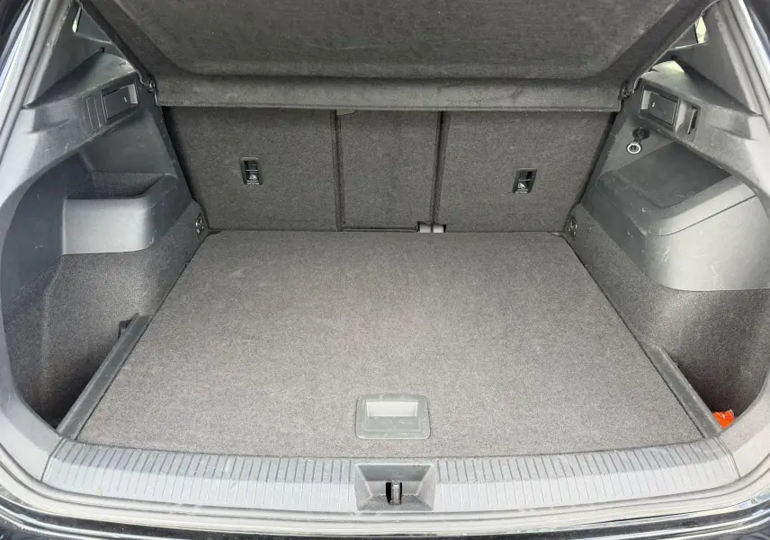 Coffre ouvert vu de l'arrière d'un Volkswagen Tiguan noir, espace de chargement propre et bien agencé.