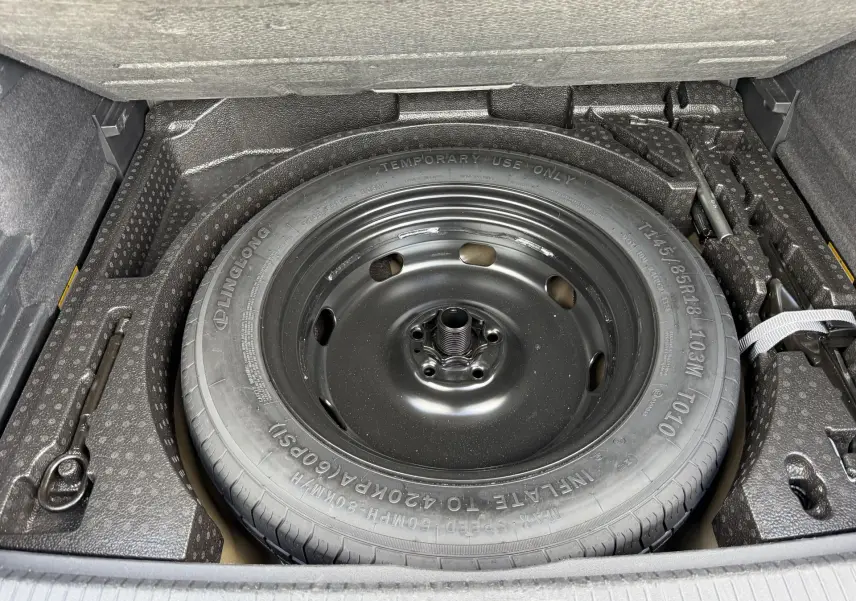 Vue rapprochée de la roue de secours compacte noire dans le coffre du Volkswagen Tiguan 2025.