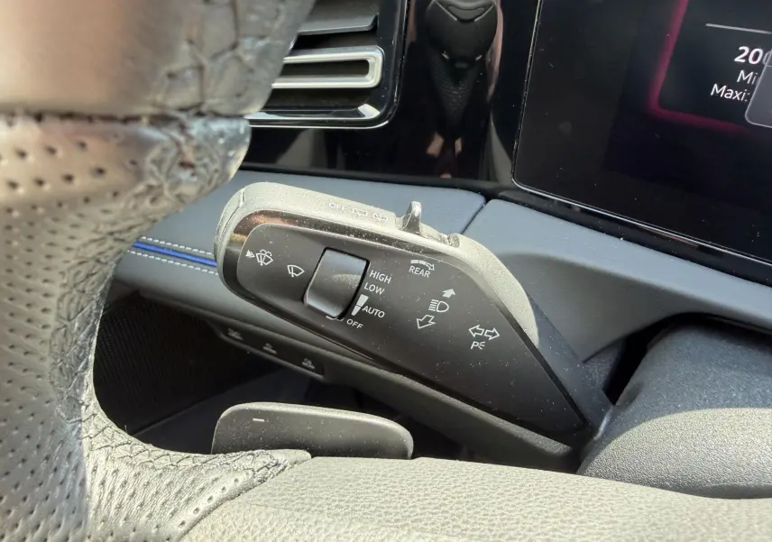 Gros plan sur la commande de l’essuie-glace côté gauche du volant cuir perforé dans l’habitacle noir du Volkswagen Tiguan 2025.