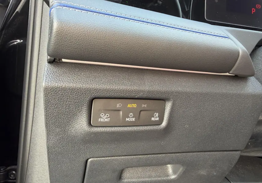Gros plan sur la commande d’éclairage noire avec mode automatique, sur la partie inférieure gauche du tableau de bord du Volkswagen Tiguan noir.