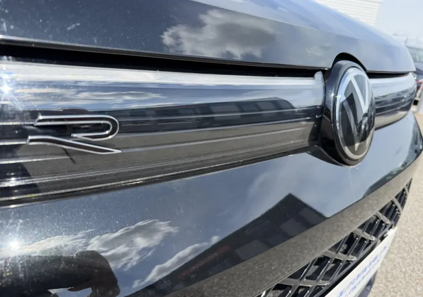 Gros plan sur la calandre avant noire du Volkswagen Tiguan 2025 avec logo VW et sigle R brillant.
