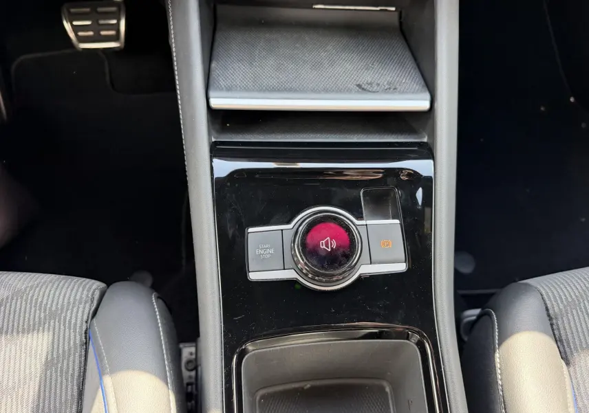 Vue plongeante sur la console centrale noire du Volkswagen Tiguan 2025, avec bouton Start/Stop et frein à main électronique.