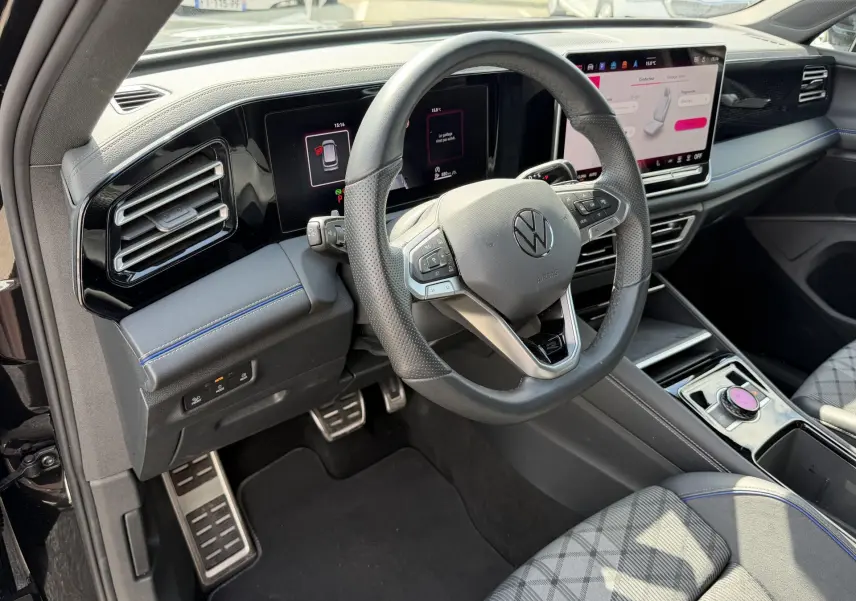 Vue intérieure côté conducteur du Volkswagen Tiguan 2025 noir, volant cuir multifonction et écran digital tactile.