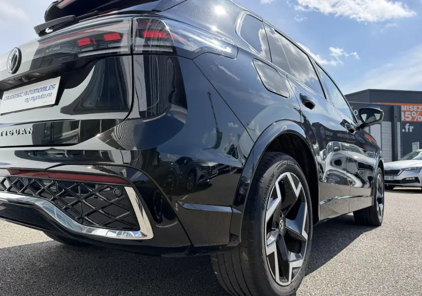 Vue 3/4 arrière droite du Volkswagen Tiguan noir 2025 avec jantes alliage 19 pouces et feux arrière LED 3D visibles.