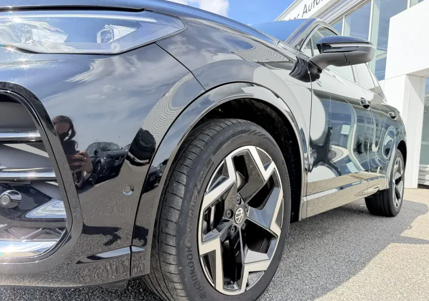 Vue 3/4 avant droit du Volkswagen Tiguan noir brillant mettant en valeur la jante alliage 19 pouces et le rétroviseur avec clignotant intégré.