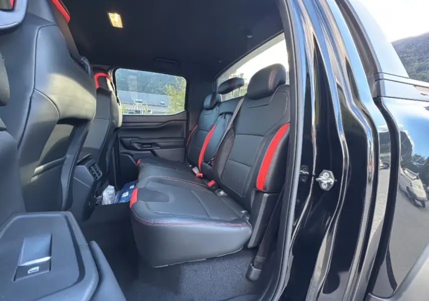 Vue intérieure côté droit arrière du Ford Ranger Raptor 2024 noir absolu, sièges en cuir noir avec surpiqûres rouges.