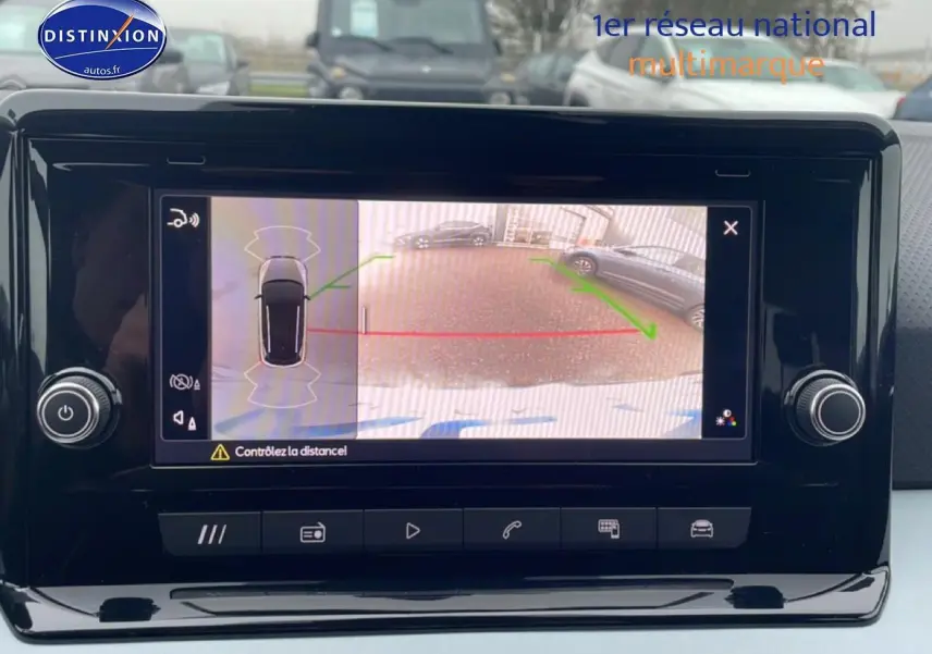 Écran de caméra de recul affichant une SEAT Arona blanc Nevada vue de l'arrière en stationnement.