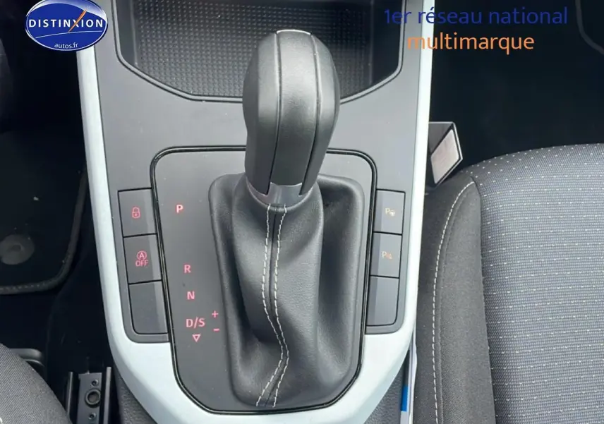 Levier de boîte automatique noir avec coutures blanches, console centrale et siège tissu gris dans une SEAT Arona 2025.