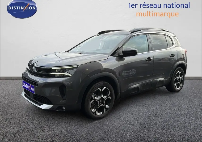 Vue 3/4 avant d'un Citroën C5 Aircross gris platinium métal avec jantes noires et toit ouvrant.