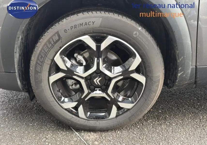 Gros plan sur la roue avant gauche du Citroën C5 Aircross gris platinium métal avec jante alliage noire et argentée.