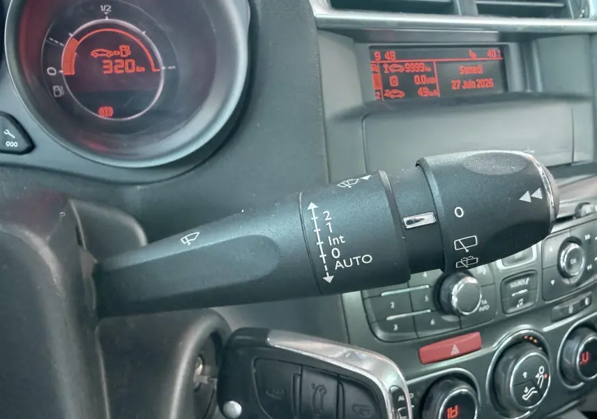 Gros plan sur la commande d’essuie-glace et le tableau de bord numérique rouge d’une Citroën C4 gris, intérieur noir.