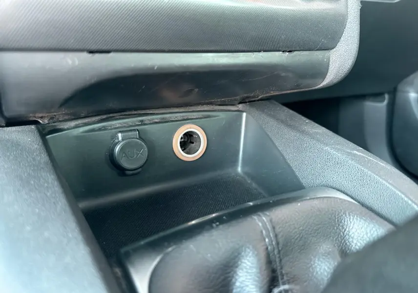 Gros plan sur la prise AUX et l’allume-cigare dans l’habitacle noir d’une Citroën C4 gris 2011.