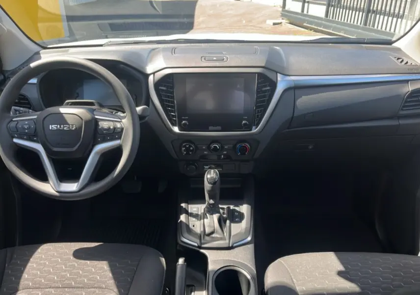 Vue intérieure frontale de l'Isuzu D-MAX 2026 avec tableau de bord noir et écran tactile central éteint.