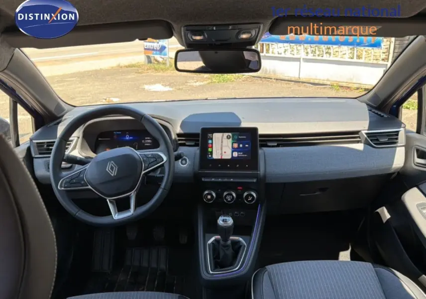 Vue intérieure avant de la Renault Clio 2025 bleu iron metal, tableau de bord moderne avec écran tactile et volant multifonction.