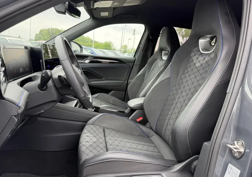 Intérieur côté conducteur du Volkswagen Tiguan gris 2025, sièges sport avec surpiqûres bleues et tableau de bord digital.