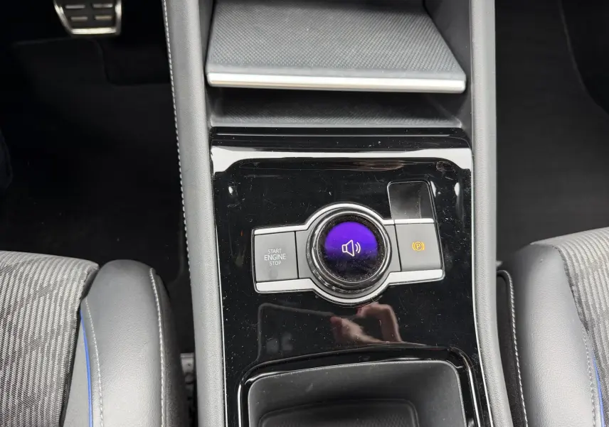 Gros plan sur la console centrale noire brillante du Volkswagen Tiguan 2025 avec bouton start/stop et frein à main électronique.
