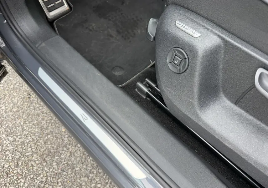 Gros plan sur le seuil de porte côté conducteur gris du Volkswagen Tiguan avec réglage siège ErgoActive visible.
