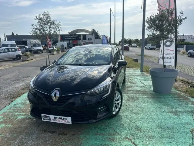 Renault Clio 1.0 TCE Evolution noir vue 3/4 avant droit, stationnée en extérieur sur sol vert avec reflet du ciel sur la carrosserie.